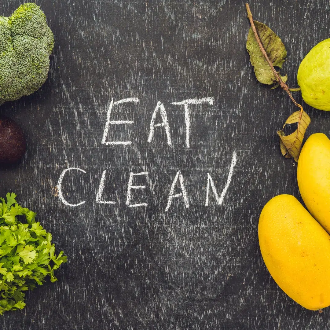 Eat clean: chalkboard message surrounded by fruits and vegetables promoting minimal processed foods and low refined sugar.