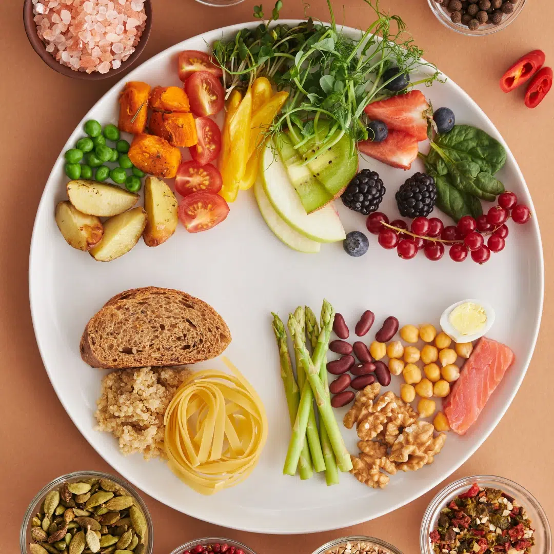 Anti-estrogen foods plate: colorful produce, whole grains, beans, nuts, asparagus, salmon, and greens portioned on a large dish.